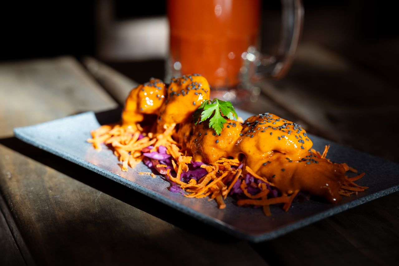Delicious spicy Asian dumplings served on a decorative plate with garnish and sauce.